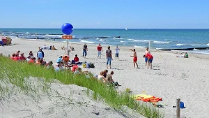 Rettungsschwimmer bewachen im Sommer den Badestrand, Jugendliche spielen Beachvolleyball